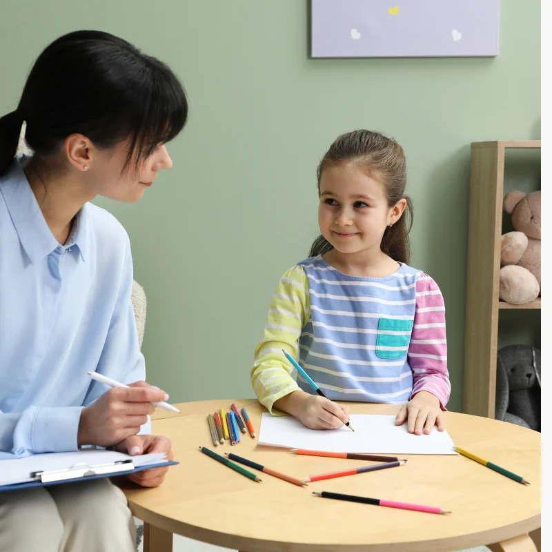 مربی در حال ارزیابی کودک خندان با مداد و کاغذ برای تست بیش‌فعالی