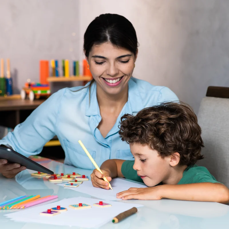 کودک در حال انجام تکالیف نوشتاری با حمایت و تشویق مادر یا مربی