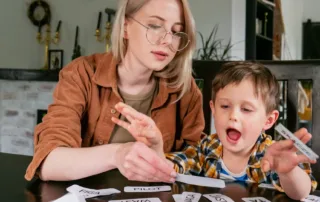مادری که به کودک اوتیسم خود با کارت‌های حروف آموزش می‌دهد، نشان‌دهنده روش‌های آموزشی اوتیسم است.
