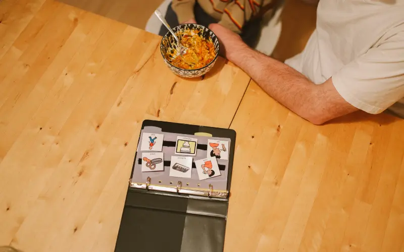 چند تصویر مختلف روی میز برای آموزش روش PECS به کودکان اتیسم، روشی برای ارتباط غیرکلامی.