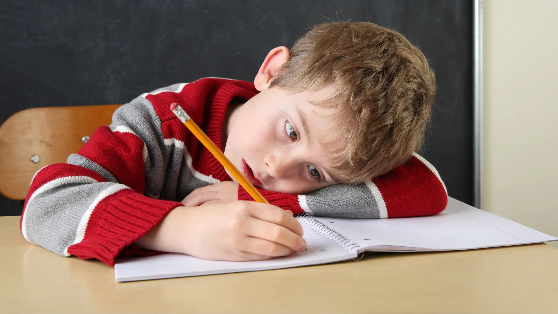 کودک ناراحت در حال نوشتن؛ نشانه‌های اختلال نوشتن (دیسگرافیا)